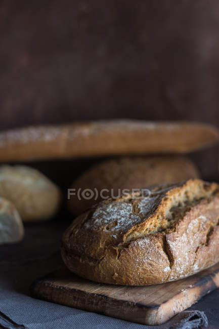Vista de perto de loafs de pão caseiros frescos no tabuleiro rústico — Fotografia de Stock