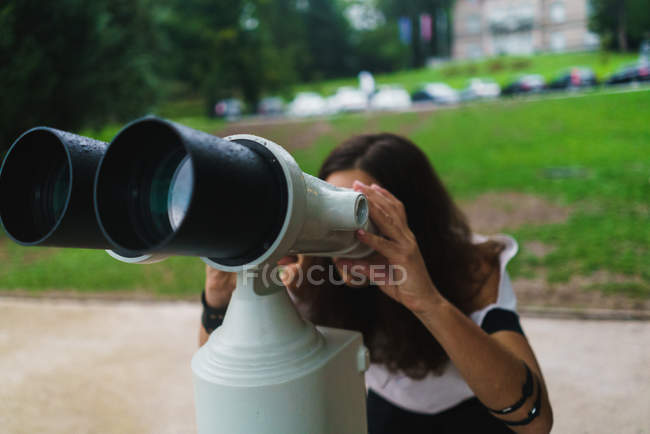 Retrato de mujer mirando la máquina binocular de turismo en el parque . - foto de stock