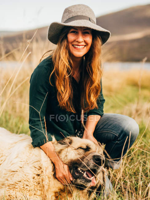 Porträt einer lächelnden Frau mit Hund auf dem Feld — Stockfoto