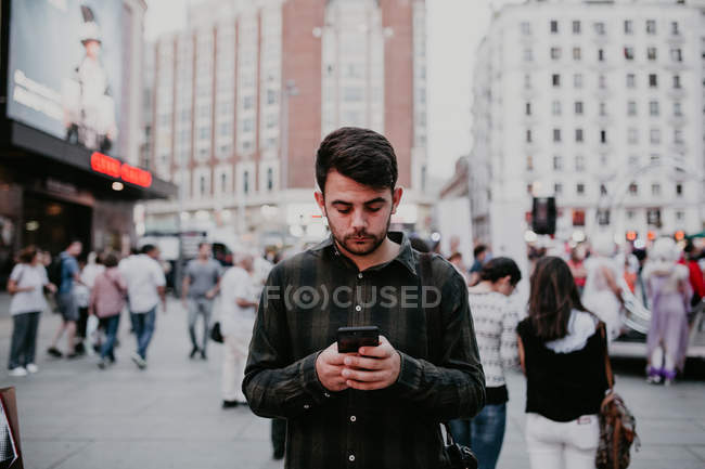 Человек просматривает смартфон на городской улице — стоковое фото