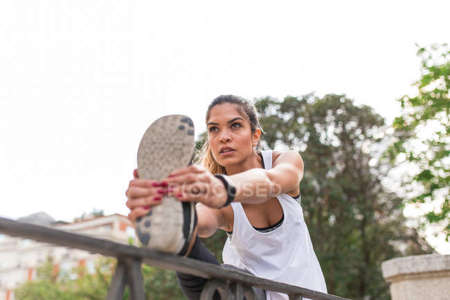 Fit girl stretching leg and looking away — Stock Photo