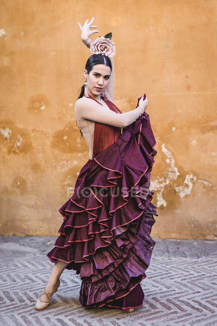 Flamenco dancer wearing typical costume with long skirt posing over street wall — Stock Photo