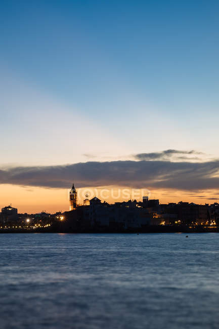 Vue lointaine de la silhouette de la ville côtière sur le paysage nuageux du coucher du soleil — Photo de stock