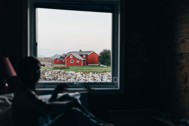 Blick auf ländliche rote Hütten durch Fenster in dunklen Raum — Stockfoto