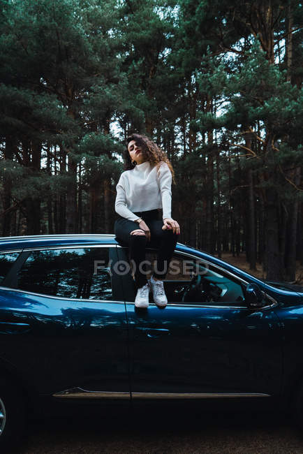 Portrait de femme brune assise sur le dessus de la voiture — Photo de stock