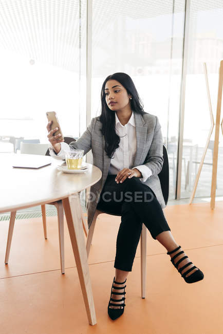 Porträt einer Geschäftsfrau, die beim Tee auf dem Smartphone surft — Stockfoto