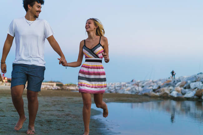 Ridendo coppia a piedi sulla spiaggia e guardando l'un l'altro — Foto stock