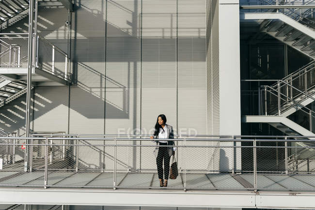 Elegant businesswoman looking down from modern balcony — Stock Photo