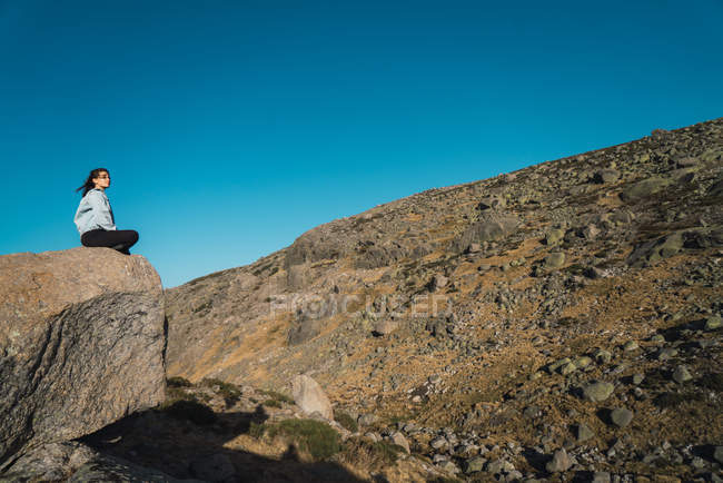Женщина, сидящая на камнях в сухой горной местности — стоковое фото
