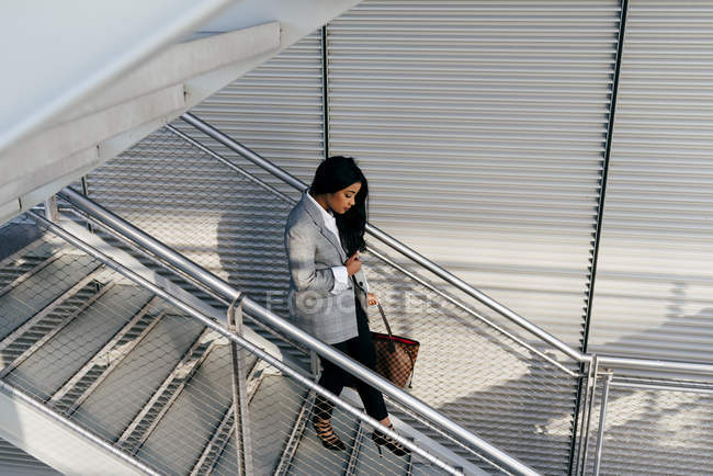 High angle view of elegant businesswoman looking down and carefully walking down stairs — Stock Photo