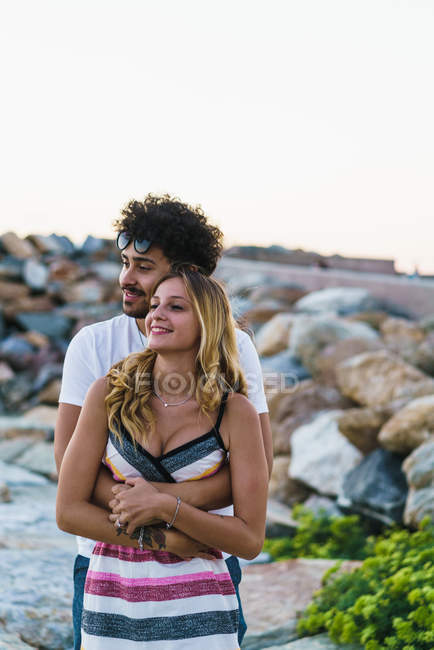 Abrazando pareja posando sobre rocas costeras - foto de stock