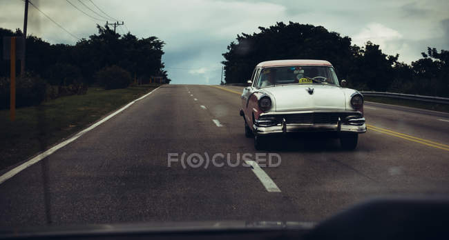 Kuba - 27. August 2016: weißes Retro-Auto fährt auf tropischer Straße — Stockfoto