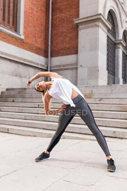 Портрет спортивной девушки, растянувшейся на улице — стоковое фото