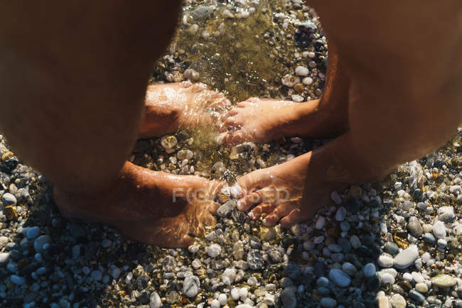 Crop of two people standing in shallow water — Stock Photo