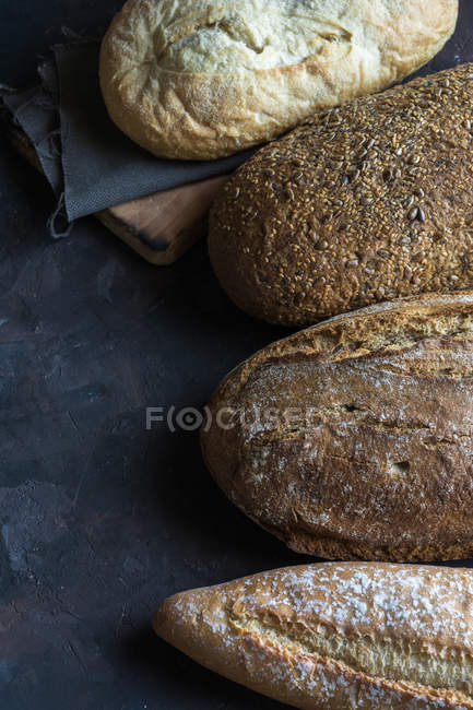 Vue de dessus de différents types de pain fait maison sur la table rustique . — Photo de stock