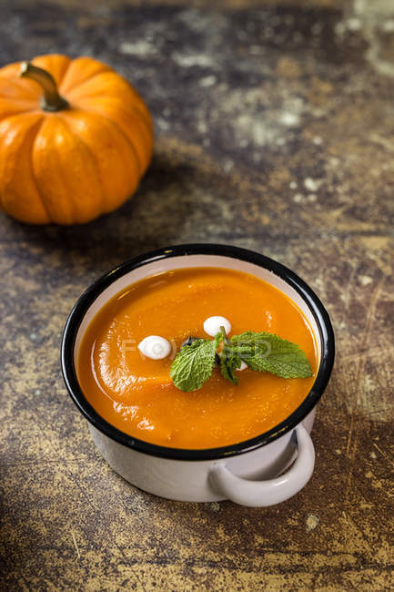 Close up view of cream of pumpkin in white sauce pot on stone surface — Stock Photo
