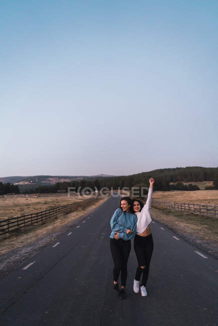Retrato de dos mujeres alegres caminando por el camino rural - foto de stock