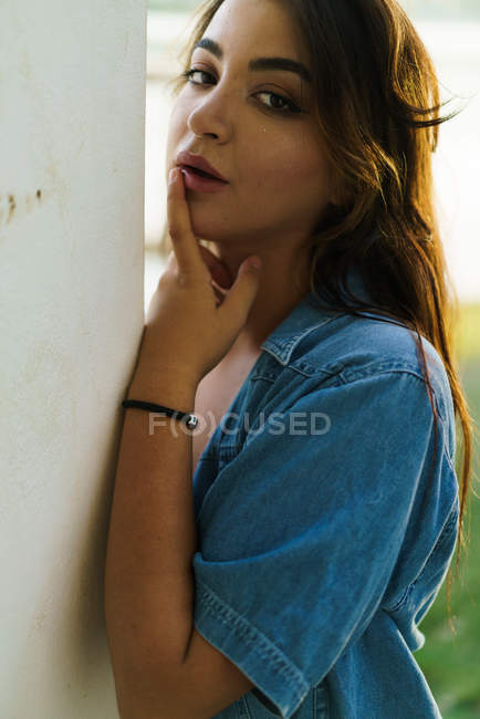 Stylish confident brunette posing at camera with finger on lips — Stock Photo