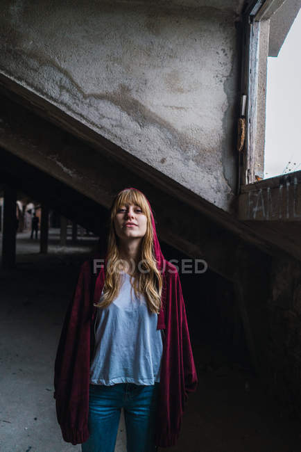 Woman in red jacket posing in derelict building — Stock Photo