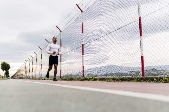 Vista superficiale dell'uomo che corre lungo la recinzione — Foto stock