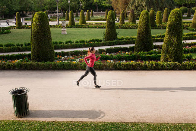 Side view of athletic girl jogging on park alley — Stock Photo