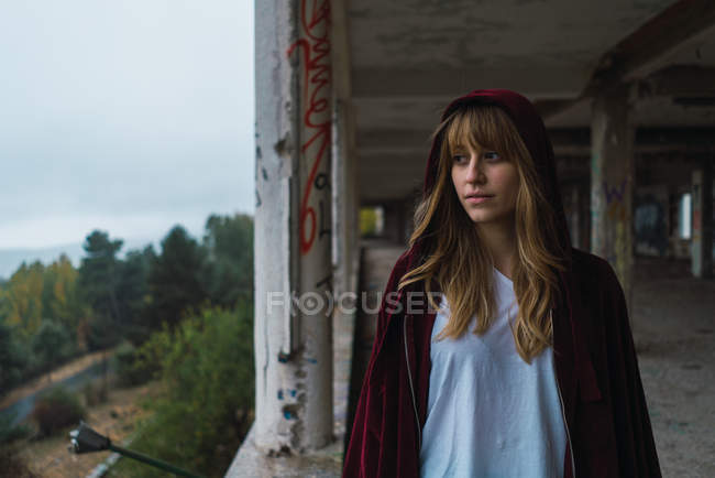 Woman in red hoodie posing at derelict building — Stock Photo