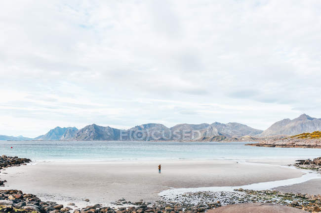 Далекий задний вид человека, стоящего на берегу океана — стоковое фото