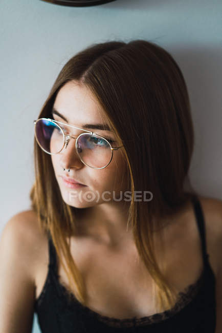 Portrait de jeune brune aux lunettes détournant les yeux — Photo de stock