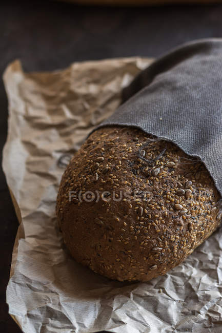 Close up view of fresh baked home-made bread on paper covered with fabric — Stock Photo
