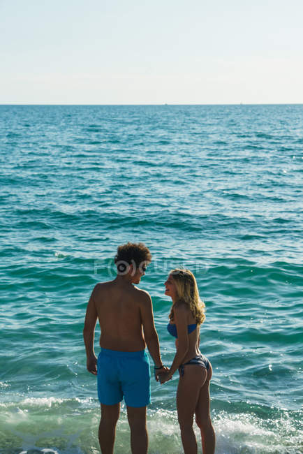 Vue arrière du couple posant au bord de l'océan — Photo de stock