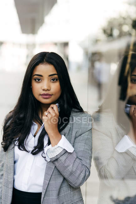 Portrait of elegant woman posing near shop window and looking at camera — Stock Photo