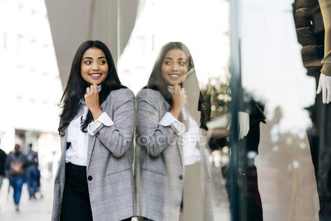 Woman posing with finger on chin and looking at shop window — Stock Photo
