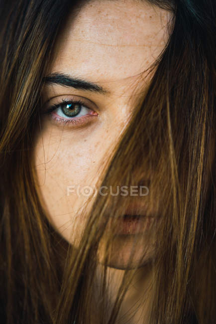 Porträt eines brünetten Mädchens mit Haaren im Gesicht, das in die Kamera schaut — Stockfoto
