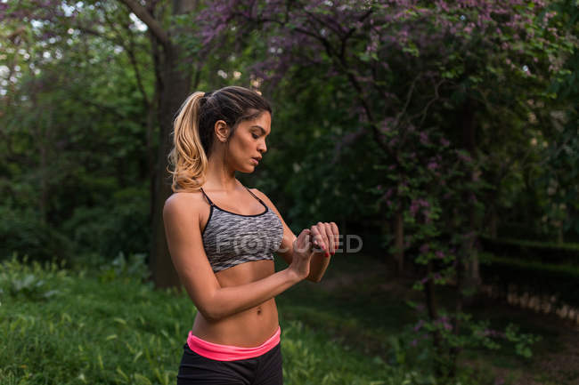 Sportliches Mädchen blickt im Park auf Armbanduhr — Stockfoto