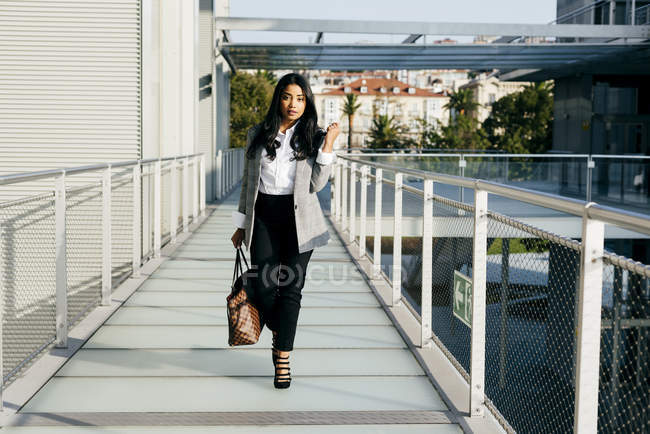 Елегантний бізнес-леді ходіння по проходу балкон і дивлячись на камеру — стокове фото