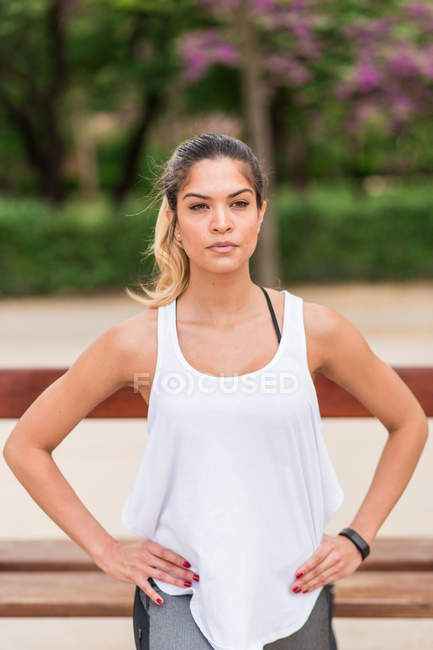 Portrait of concentrated sporty girl posing with hands on waist at park — Stock Photo