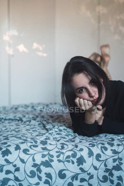 Vista frontale della donna sdraiata a letto e guardando la fotocamera — Foto stock