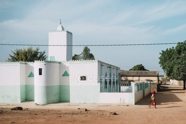 Goree, Senegal- Dezembro 6, 2017: Vista lateral do pedestre caminhando ao longo do edifício branco em luz solar brilhante . — Fotografia de Stock