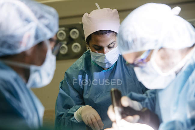Retrato de mujer en uniforme médico preparando instrumentos para cirujanos en quirófano - foto de stock
