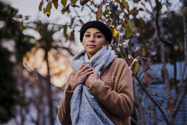Donna posa vicino albero con luci — Foto stock