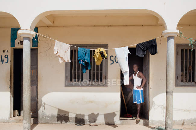 Goree, Sénégal- 6 décembre 2017 : Un Africain à la porte d'une pauvre maison avec du linge suspendu au soleil
. — Photo de stock