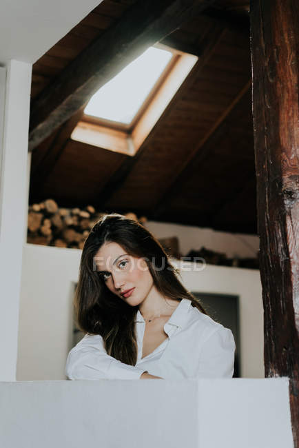 Menina morena encantadora em camisa branca posando em casa — Fotografia de Stock