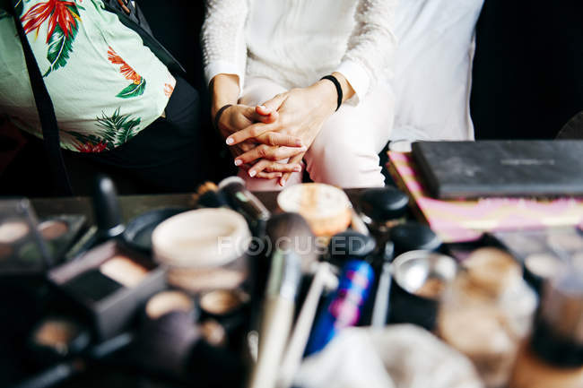 Mulher de colheita sentada perto da mesa de maquiagem com vários cosméticos . — Fotografia de Stock