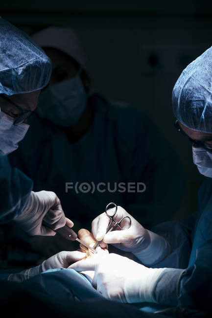 Grupo de cirurgiões que trabalham com o paciente no hospital — Fotografia de Stock