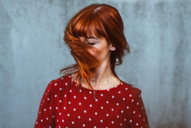 Експресивна руде волосся жінка в полка крапки візерунком сукні махає волоссям — стокове фото