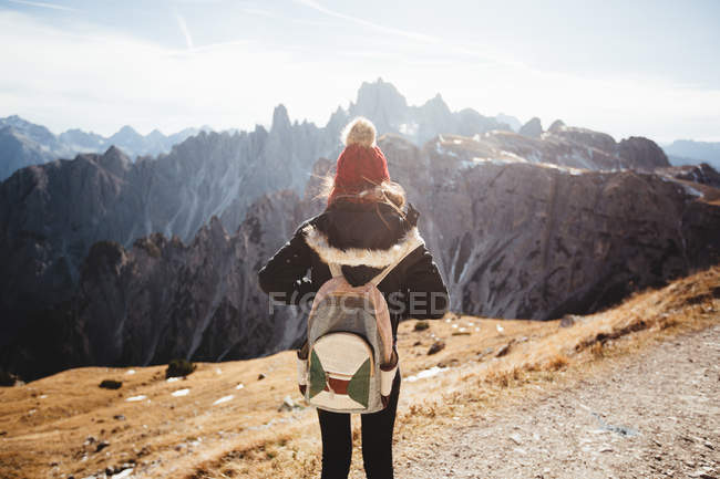 Unrecognizable woman with backpack enjoying view of mountains on sunny day. — Stock Photo