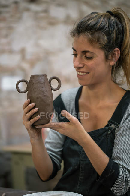 Lächelnde Frau formt Topf aus Ton in Werkstatt — Stockfoto