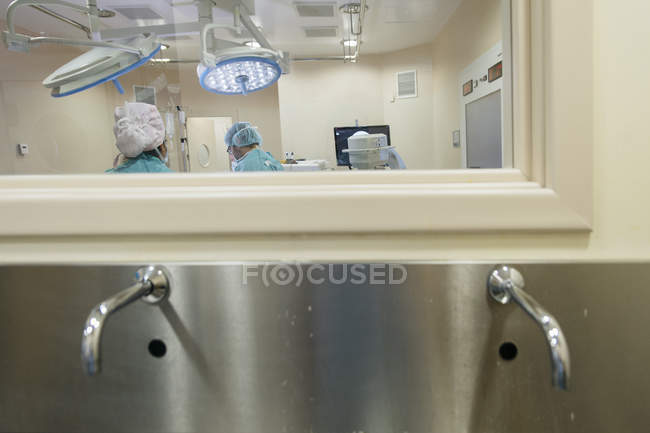 Tiro através de vidro de trabalhadores médicos na sala de cirurgia procedimento de condução . — Fotografia de Stock