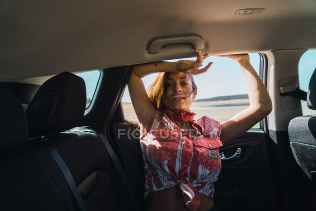Portrait of young woman hanging out of car window — Stock Photo