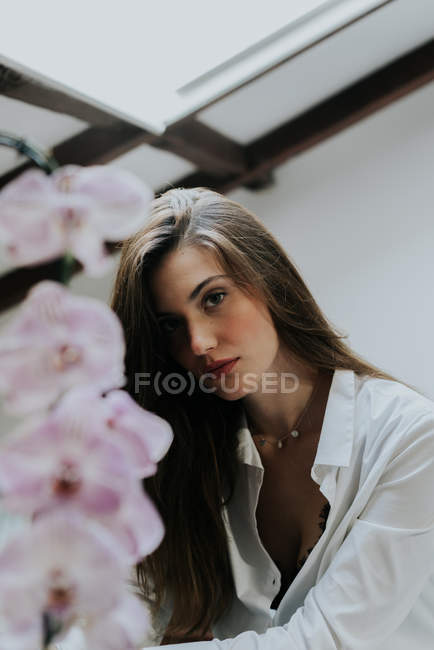 Portrait de fille brune dans la pose occasionnelle près de fleur d'orchidée — Photo de stock